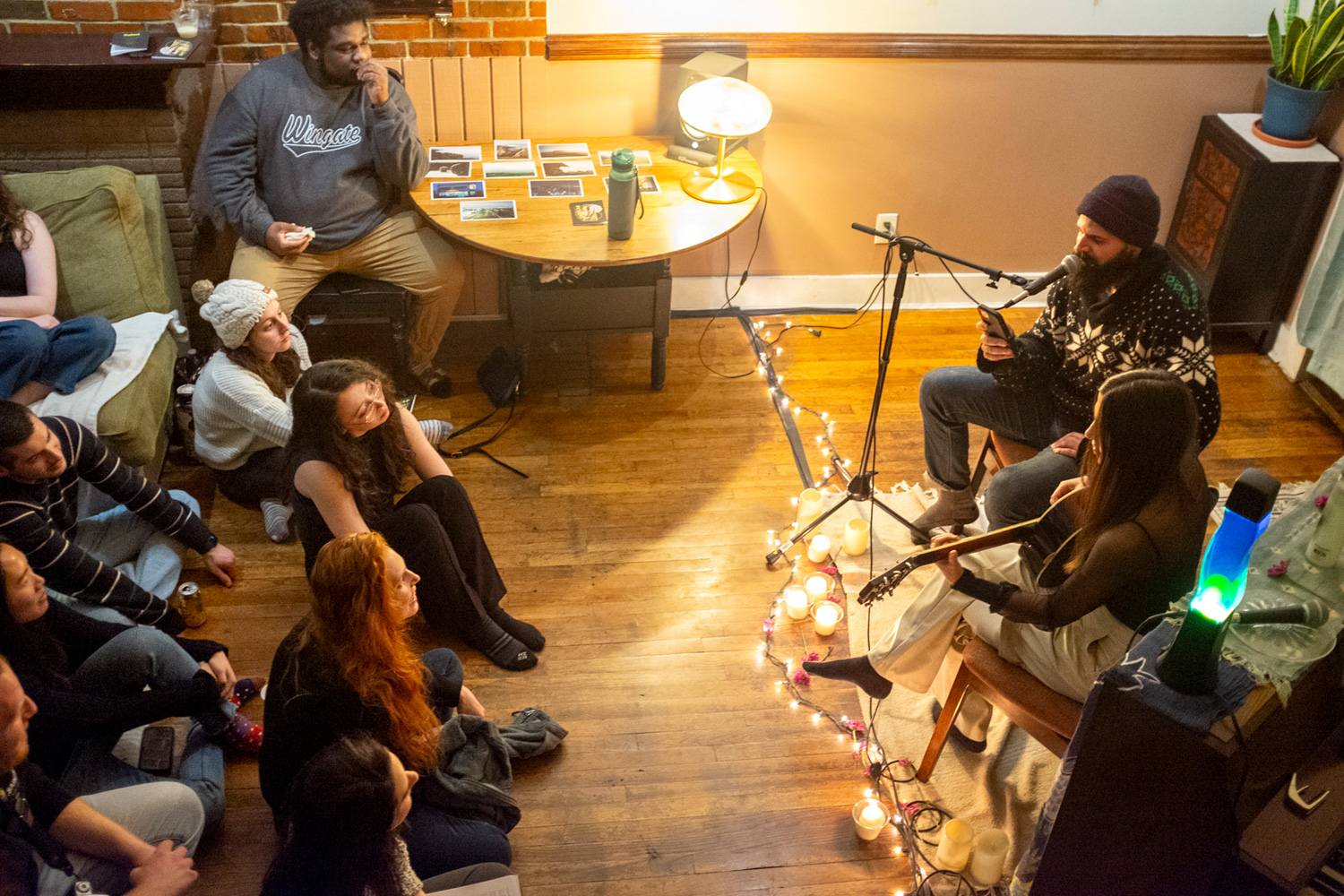 A view from above as Charlie Levine and Lexi Vollero perform together in front of the audience, seated just feet away on the shared hardwood floor, during the first ever Salad.