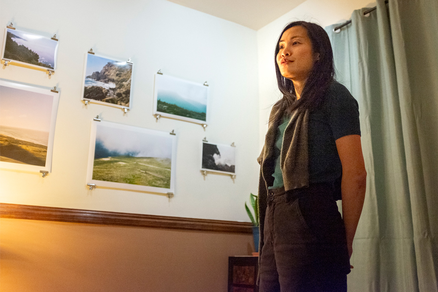 Eve Wong, speaking in the foreground, presents her photographs, hanging on the wall behind her, during the first Salad.